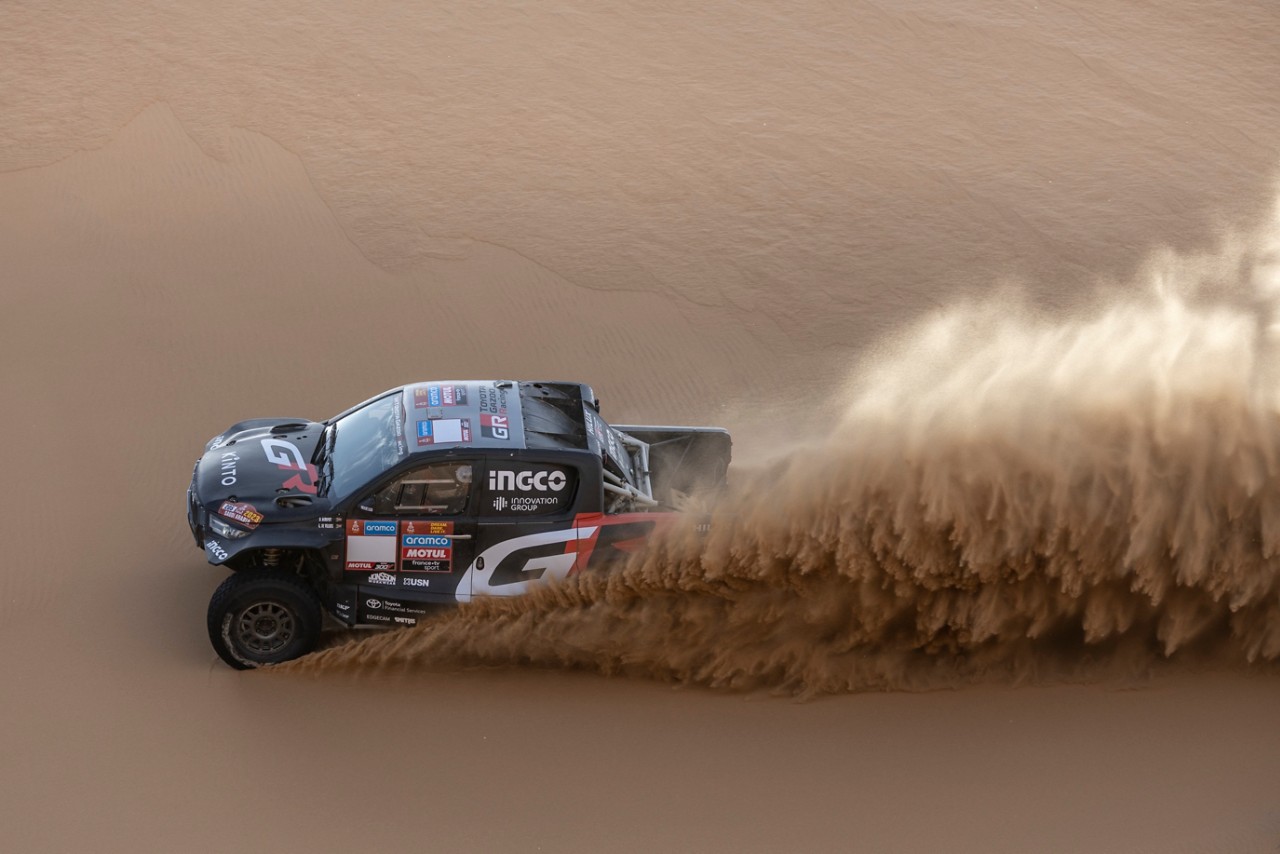 Hilux jadący przez pustynię, wzbijający piasek