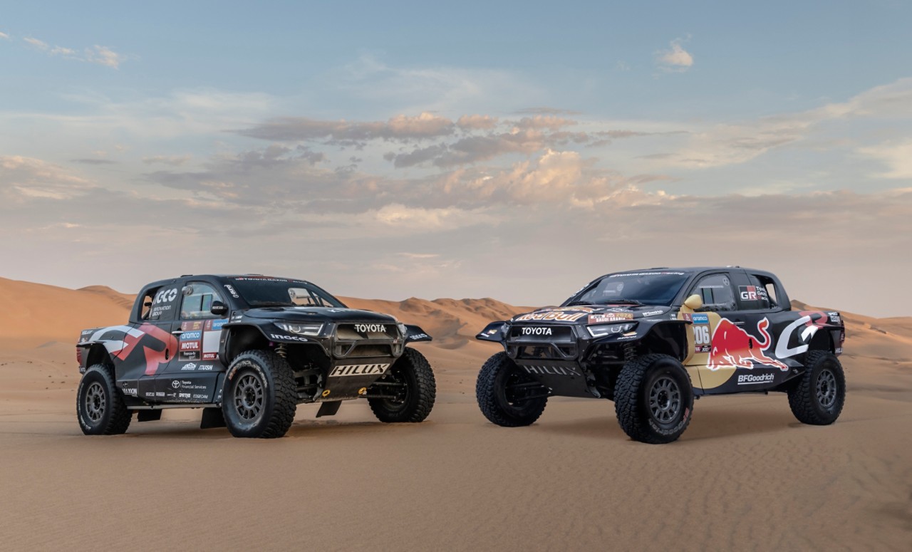 Statyczne zdjęcie 3/4 dwóch rajdowych modeli Toyoty Hilux na pustyni